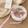 Rosafarbene Satin-Schleifen-Haarspange auf einem minimalistischen weißen Dekotablett - Rosa