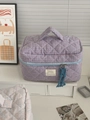 Detail of checkered makeup bag featuring soft quilting and a blue tassel zipper pull - Makeup Bag / Purple