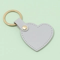 Minimalist heart-shaped leather keychain in light gray with gold metal ring and stitching - Gray