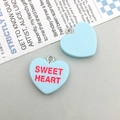 Macro shot of light blue heart-shaped resin charms with SWEET HEART text on vintage paper - Blue Letter Heart