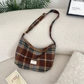 Detailed close-up of brown plaid wool hobo bag with adjustable strap on a sofa - Brown Plaid