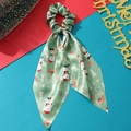 Detail of green Christmas scrunchie with long ribbons featuring festive satin patterns - Green