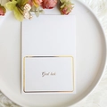 Weiße Grußkarte mit goldenem Good Luck Text auf einem stilvoll dekorierten Teller - Viel Glück