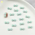 Mint green resin bow nail charms with pink dots on white plate for DIY manicure art - Lake Blue