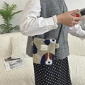 Detail of plush crossbody bag with dog pattern and polka dot strap shown on model - Camel Dog Pattern