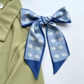 Blue and white silk scarf with geometric pattern tied in a bow on a green blazer - Blue Double C Buckle