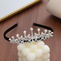 Detail of silver crown headband with sparkling rhinestones and pearls on black velvet base - Crown