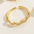 Close-up of 14K gold plated wave ring featuring pink zircon stones on a white texture - Wave / Pink Zirconia