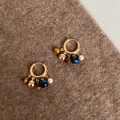 Detalle de pendientes en oro 18k con ojo de tigre, perlas y metal sobre tejido marrón - Estilo Borla Ojo de Tigre Azul / Dorado-Azul