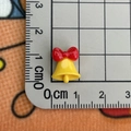 Macro shot of tiny yellow resin bell with red bow on a measuring board for nail art - Bell