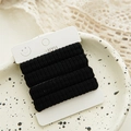Macro view of four thick black seamless hair ties on white display card packaging - Solid Black (4 Pcs/Card)