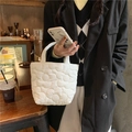 Primer plano del bolso blanco acolchado con textura floral en el entorno de un café - Blanco