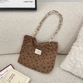 Macro of corduroy tote texture with bow patterns and beaded strap on white sofa - Brown