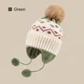 Green knit winter earflap hat for kids featuring geometric patterns and a brown pom-pom - Pompom Strap Style / Green