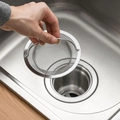 Stainless steel kitchen sink strainer basket with handle being held over a drain - Fine Mesh Style