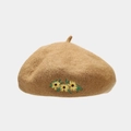 Close-up of camel wool beret featuring yellow sunflower embroidery and felt texture - Camel