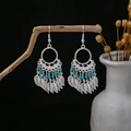 Detail of Bohemian silver leaf earrings with blue beads hanging on a rustic wooden branch - Blue
