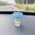 Blue artificial flower in transparent glass vase on car dashboard with Good Luck label - Blue Baby's Breath