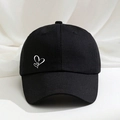 Classic black cotton baseball cap with white heart embroidery on a soft fabric backdrop - Black