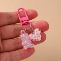 Pink resin bear keychain with glitter heart charm shown in hand for size visualization - Pink