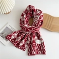 Detail of red and white knitted scarf with Nordic snowflake patterns and brand label - Geometric Circle Red