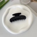 Detailed shot of a black acetate hair claw clip with colorful rhinestones in a tray - Ear Design With Black Teeth Claw Clip / Black