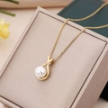 Elegante collana di perle dorate con ciondolo di zirconi su una scatola per gioielli beige - Sacchetto della Fortuna Bianco / Catena a O