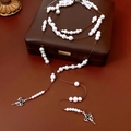 Detail van glaskraal ketting met zilveren kruishanger op een lederen juwelendoosje - Ketting-Zilver-Parel Kruis