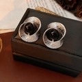 Vue macro de boucles d'oreilles argentées torsadées avec perle noire sur fond vintage - Argent Noir (Tige en Argent)