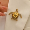 Vintage golden turtle brooch with textured shell on a white blazer lapel - Antique Gold