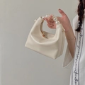 Detalle de un bolso de mano blanco crema con asa de perlas de lujo y cremallera dorada - Beige