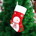 Knitted red Christmas stocking with snowman motif hanging on a decorated tree - Snowman