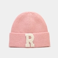 Gros plan sur le bonnet en maille rose avec un grand écusson en peluche blanche lettre R - Rose Clair