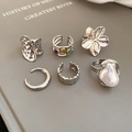 Close-up of six-piece silver ring set with floral textures and baroque pearls on book - Silver (6-Piece Set)