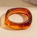 Macro shot of amber resin bangle showing detailed gradient swirls and light refraction - Dark Coffee