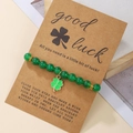 Detalle de pulsera de cuentas verdes con trébol sobre tarjeta de regalo kraft - Estilo Trébol de Cuentas Verdes (D1481-1)