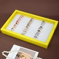 Yellow jewelry display box with 100 slots showing various gold and silver gemstone rings - Yellow