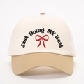 Close-up of contrast color baseball cap with Just Doing MY Best embroidery and red bow - Off-White/Dark Khaki