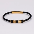 Dettaglio di bracciale in pelle nera intrecciata con perline d'oro e chiusura - Oro