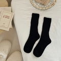 Classic black ribbed knit crew socks displayed in a cozy lifestyle setting with soft tones - One Size / Black