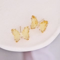 Macro view of butterfly earrings with yellow stones and white zircon on ceramic plate - Yellow
