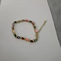 Dettaglio macro di ciondoli occhio del diavolo smaltati su bracciale placcato oro 14K - Colorato