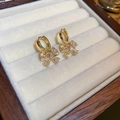 Macro-detail van vergulde strik-oorbellen met zirkonia op een zacht beige fluwelen kussen - Gouden Strass Strik Stijl (18#)