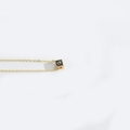 Minimalist necklace featuring a black cube pendant with a golden letter 'a' detail - Letter Q