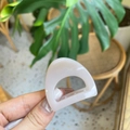 Primer plano de una pequeña pinza de pelo triangular rosa crema sostenida con fondo natural - Mini Oreja de Gato / Rosa Nude Claro