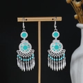 Detail view of silver bohemian tassel earrings with turquoise beads on a display stand - E2878-2 Cyan Tassel