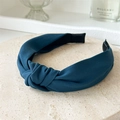 Dark teal knotted fabric headband with twill texture displayed on a beige stone base - Indigo Blue