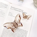 Set of transparent amber butterfly hair claws in large and small sizes on a book - Large & Small Set / Tan