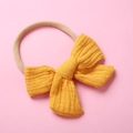 Detail of yellow cotton muslin bow headband with soft elastic nylon band for infants - Turmeric