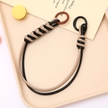 Close-up of woven black and beige leather strap with dual metal ring buckles on a tray - Khaki & Black